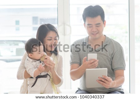 Chinese man scanning QR code with smart phone. Asian family at home, natural living lifestyle indoors.