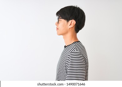 Chinese Man Wearing Glasses And Navy Striped T-shirt Standing Over Isolated White Background Looking To Side, Relax Profile Pose With Natural Face With Confident Smile.