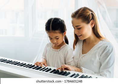 Chinese Mother Watching Young Daughter Play Keyboard