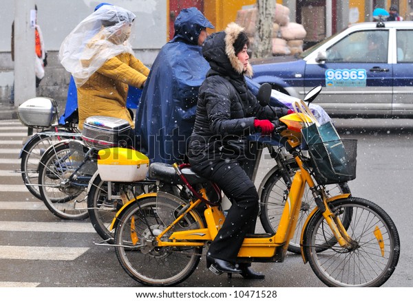 Chinese\
motorcyclist in shanghai street in a snowy\
day
