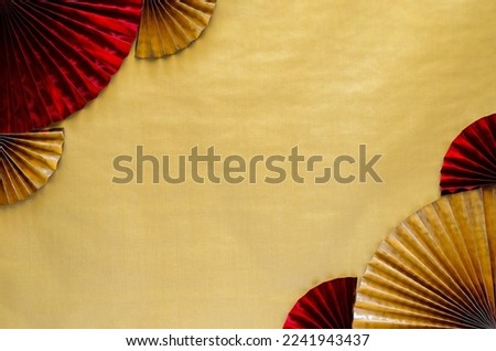 Chinese new year background concept with red and gold oriental fans on golden empty space background.