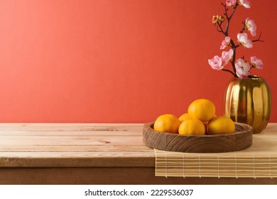 Chinese New Year celebration background with orange fruit on table and flowers decoration. Interior mock up for design and product display. - Shutterstock ID 2229536037