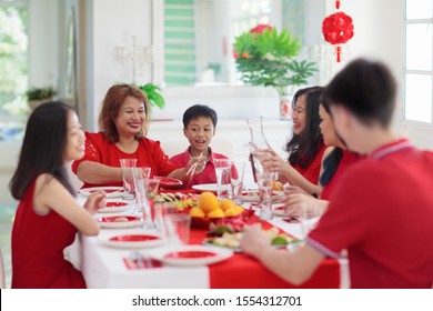 Chinese New Year Celebration. Family Celebrating Winter Holiday. Traditional Festive Dinner In China. Parents, Grandparent And Kids Eating And Giving Red Ang Pao Envelopes To Children. Home Decoration