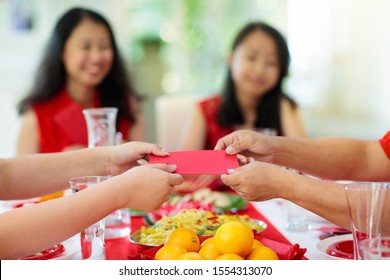 Chinese New Year Celebration. Family Celebrating Winter Holiday. Traditional Festive Dinner In China. Parents, Grandparent And Kids Eating And Giving Red Ang Pao Envelopes To Children. Home Decoration