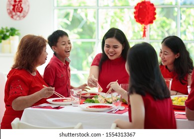 Chinese New Year Celebration. Family Celebrating Winter Holiday. Traditional Festive Dinner In China. Parents, Grandparent And Kids Eating And Giving Red Ang Pao Envelopes To Children. Home Decoration