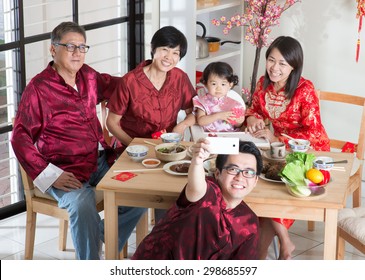 Chinese New Year Celebration, Reunion Dinner. Happy Asian Chinese Multi Generation Family With Red Cheongsam Selfie While Dining At Home.