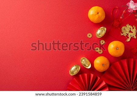 Chinese New Year essentials in one frame: top view of fans, Feng Shui trinkets, coins, sycee, red envelopes, dragon charm wall hanging, tangerines on red surface, offering ideal spot for text or ads