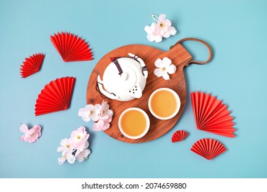 Chinese new year festival decoration over blue background. Traditional lunar new year flat lay with green tea, red paper fans, cherry blossom. Top view - Powered by Shutterstock