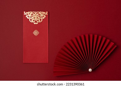 Chinese new year festival decoration over red background. traditional lunar new year red pockets, paper fan for fortune, prosperity, wealth. Flat lay, top view - Shutterstock ID 2231390361