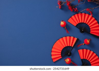 Chinese New Year folding fans, lanterns, cherry blossom branch on dark blue background. Happy Lunar New Year concept. - Powered by Shutterstock