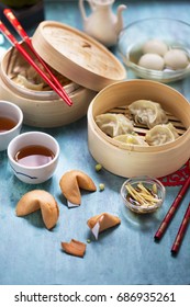 Chinese New Year Food And Drinks, Steamed Dumpling In Bamboo Steamer,  Fortune Cookies On Wooden Blue Table Top. Close Up View.