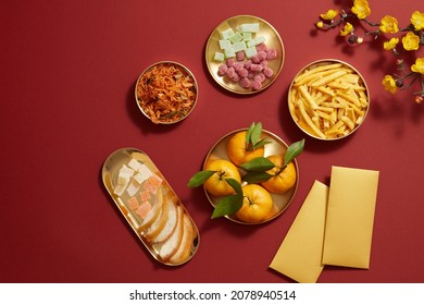 Chinese new year holiday with mandarin orange candy jam , fried potato , flower and red pocket biscuit in golden dish , photography Tet holiday content , top view