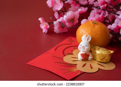 Chinese New Year of the rabbit festival concept. Mandarin orange, red envelopes, rabbit and gold ingot decorated with plum blossom on red background.  - Shutterstock ID 2238810007