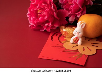 Chinese New Year of the rabbit festival concept. Mandarin orange, red envelopes, rabbit and gold ingot decorated with plum blossom on red background.  Chinese character 