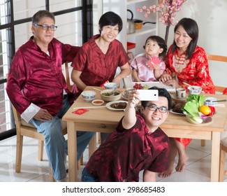 Chinese New Year, Reunion Dinner. Happy Asian Chinese Multi Generation Family With Red Cheongsam Selfie While Dining At Home.