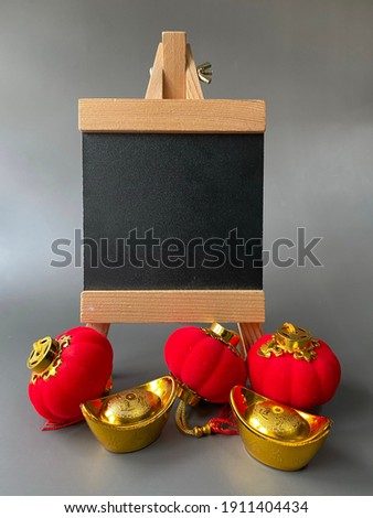 Chinese New Year sale or promo template. Red lanterns and gold ingot with blackboard on grey background. Chinese characters on gold ingot means prosperity