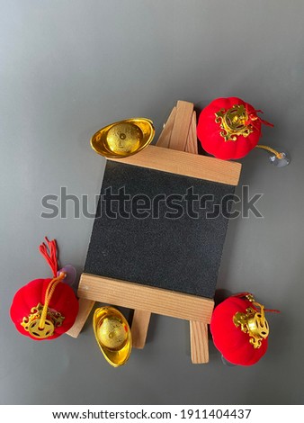Chinese New Year sale or promo template. Red lanterns and gold ingot with blackboard on grey background. Chinese characters on gold ingot means prosperity