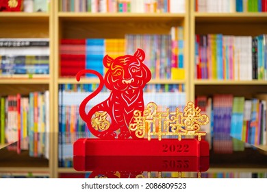 Chinese New Year of tiger 2022 mascot paper cut in a living room in front of book shelfs the Chinese means fortune and happy Chinese New Year no logo no trademark