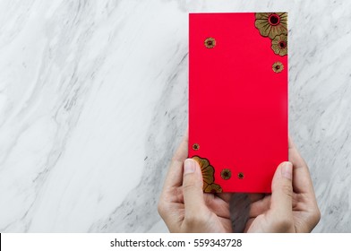 Chinese New Year. Woman Hand Holding Red Envelope On White Marble Background. Isolated. Copy Space