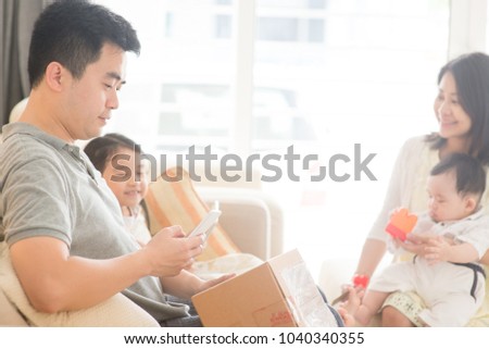 Chinese people scanning QR code with smart phone. Happy Asian family at home, natural living lifestyle indoors.