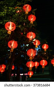 Chinese Red Cloth Lanterns For The Feast Of The Chinese New Year Hanging On A Tree At Night.