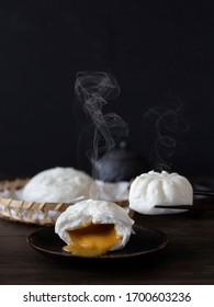 Chinese Salted Egg Bao (Bun), Yolk Flowing Out Of Chinese Bun. Salted Egg Lava Bun On Black Background. Steamed Buns With Steam With Copy Space. Side View Of Soft Buns.