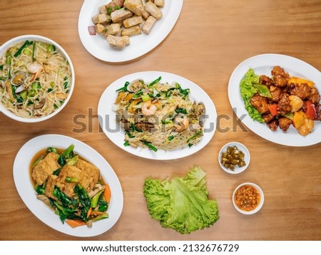 chinese seafood table Beancurd Kailan, Stir Fried yam, Xinghua Lor Mee, in a dish with chili sauce, and king's salad leaf top view on wooden background