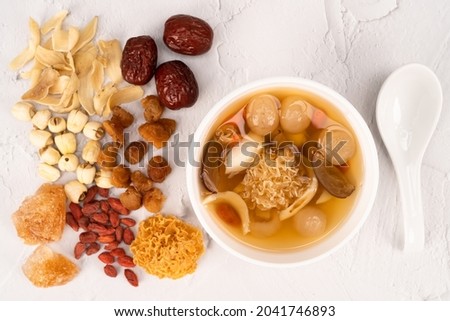 Chinese snow fungus dessert soup  with ingredients of snow fungus, dried longan, red dates, lotus seeds, lily bulbs, goji berries and rock sugar at the side