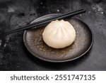 Chinese Steam Bao bun with meat on plate with chopsticks. black background. top view.