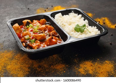 Chinese Style Chicken With White Rice, Take-out Container. Ready Dish In A Black Container. Composed Take-out Meal, Diet Catering. The Container On A Dark Background.