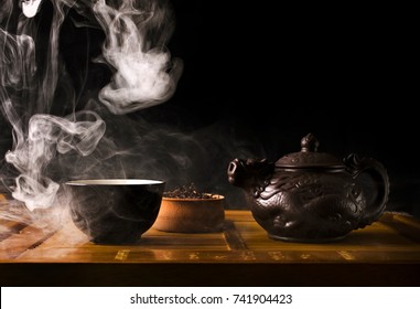 Chinese tea ceremony. Ceramic tea pot and cups with the famous chinese puerh tea with vapour on a black background. - Powered by Shutterstock