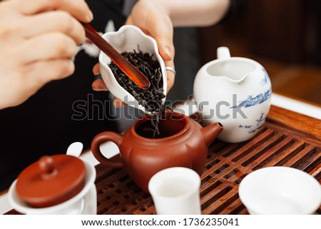 Chinese tea ceremony. Girl pours tea leaf into a teapot