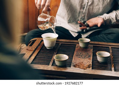 Chinese tea ceremony, a man pours tea into cups on a bamboo table chaban - Powered by Shutterstock