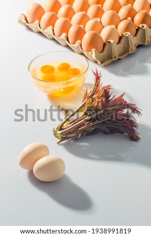 Chinese toon leaves and fresh eggs before Grain Rain are placed against a white background