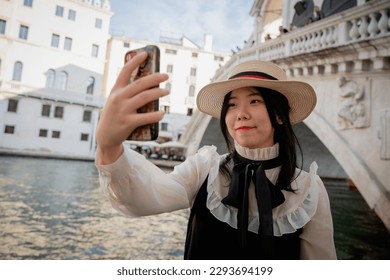 A Chinese tourist takes a selfie in front of the Rialto bridge in Venice