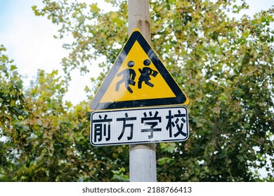 Chinese Warning sign of pedestrians crossing road ahead near school(前方学校means School Ahead)