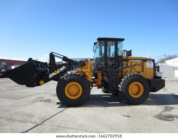 Chinese wheel front loader JinGong  in a parking lot\
for road transport, Krasnodar region, Russia, March 2, 2020.\
Special equipment for loading and transporting materials,\
earthmoving, side view