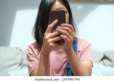 Chinese Woman Hiding Face Behind Cell Phone