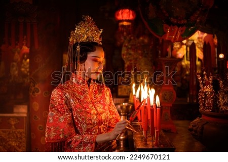 Chinese woman make wishes, pray, and light candles. On the occasion of the annual Chinese New Year festival, in a revered shrine or temple, And in Chinese where candles mean good luck and happiness