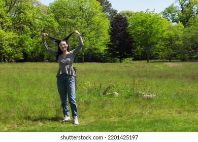 A Chinese Woman Playing With Her Hair In A Field On A Sunny Day On Martha's Vineyard. 