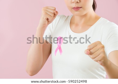 Chinese woman with ponytail make a fist to fight for female cancer disease and breast cancer and find illness out in time isolated on pink background. medical and health concept.