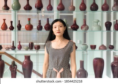 A Chinese Woman Standing Near A Shelf Of Various Vases Within The Walters Art Museum In Baltimore Maryland.