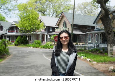 A chinese woman standing on a road through the national historic landmarks oak bluffs campground from the 19th century on martha's vineyard. - Shutterstock ID 2185699741