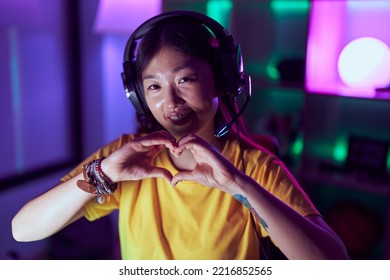 Chinese Woman Streamer Using Headset Doing Heart Gesture With Hands At Gaming Room