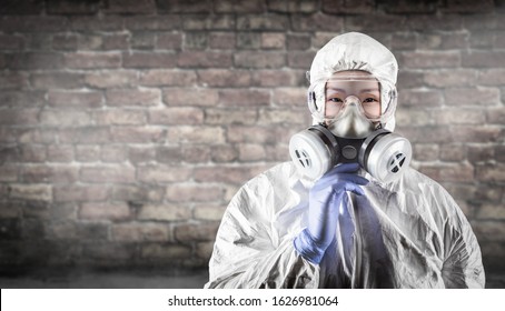 Chinese Woman Wearing Hazmat Suit, Protective Gas Mask And Goggles Against Brick Wall.