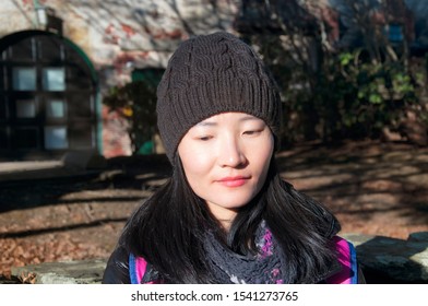 A Chinese Woman Wearing A Winter Hat And Jacket In Newport Rhode Island With A Building And Autumn Background. 