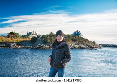 A Chinese Woman Wearing A Winter Hat And Jacket In Newport Rhode Island With Beach Houses And Autumn Background.