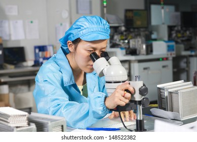 Chinese worker monitors the quality of the products by microscope on factory - Shutterstock ID 148522382