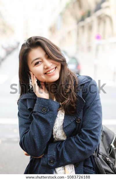 Chinese young\
female tourist standing in road background in Europe. Concept of\
tourism and international\
students.