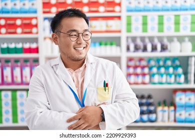 Chinese Young Man Working At Pharmacy Drugstore Looking Away To Side With Smile On Face, Natural Expression. Laughing Confident. 